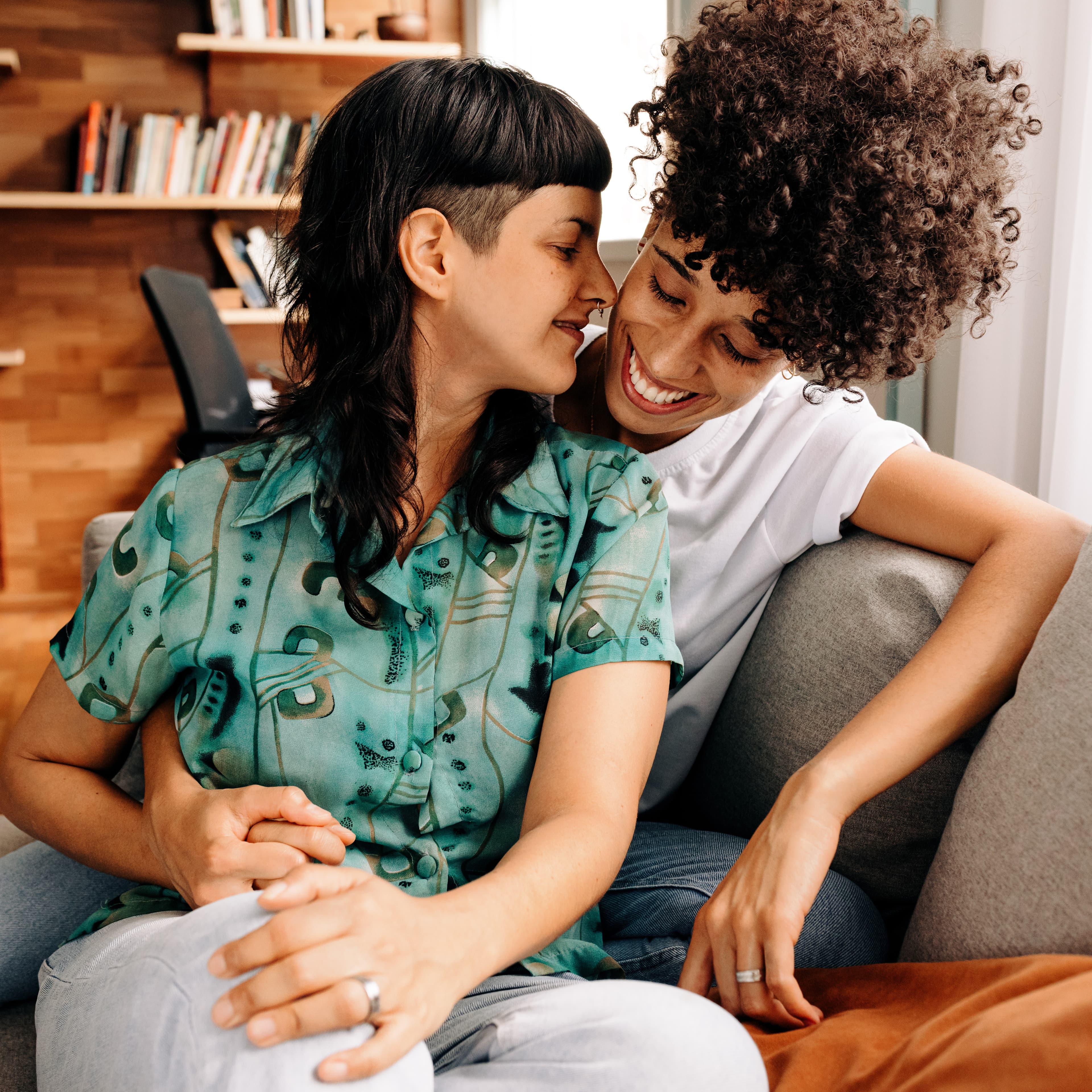 Two women hugging on couch Two women hugging on couch